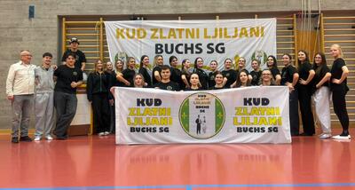 In einer Turnhalle in Buchs (9470, Kanton St. Gallen) steht eine Gruppe von Personen vor einem Banner und praesentiert gemeinsam ein Vereinsplakat.
