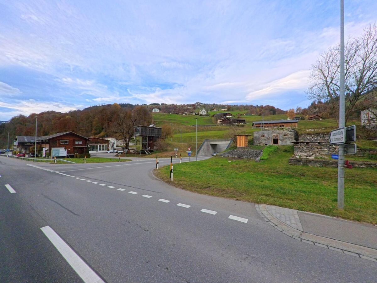 An einer übersichtlichen Kreuzung treffen Strassen und Wege im ländlich geprägten Siedlungsbereich von Küblis (7240, Kanton Graubünden) aufeinander, umgeben von grünen Hängen.
