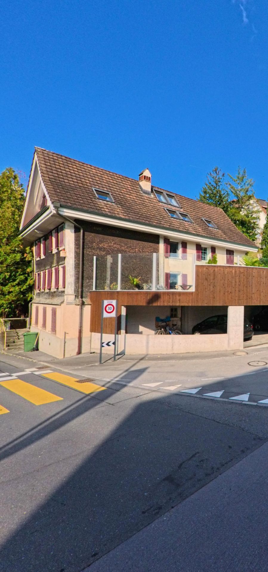 Ein traditionsreiches Wohnhaus in Kuessnacht (6403, Kanton Schwyz) steht an einer verkehrsberuhigten Strasse mit markierten Uebergaengen und einem kleinen Carport.