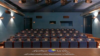 In Dietlikon (8305, Kanton Zuerich) zeigt der Kulturtreff einen kleinen Saal mit geschlossener Buehne, roten Vorhaengen und mehreren Reihen dunkler Sitzplaetze.