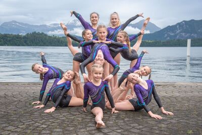 Vor dem Vierwaldstättersee zeigen die Kunstturnerinnen aus Küssnacht (6403, Kanton Schwyz) eine präzise Gruppenpose mit ausdrucksstarken gymnastischen Figuren.