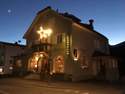 In Lenzerheide (7078, Kanton Graubuenden) zeigt sich das Restaurant La Patata bei Abenddaemmerung mit festlicher Beleuchtung und traditioneller Fassade.