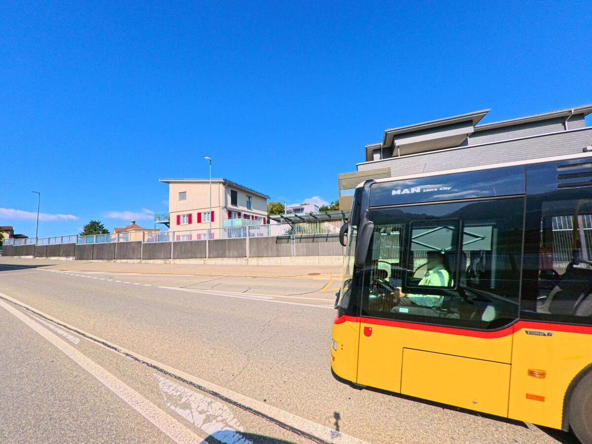 Ein Linienbus fährt an modernen Gebäuden entlang einer Hauptstrasse in Lachen (8853, Kanton Schwyz).