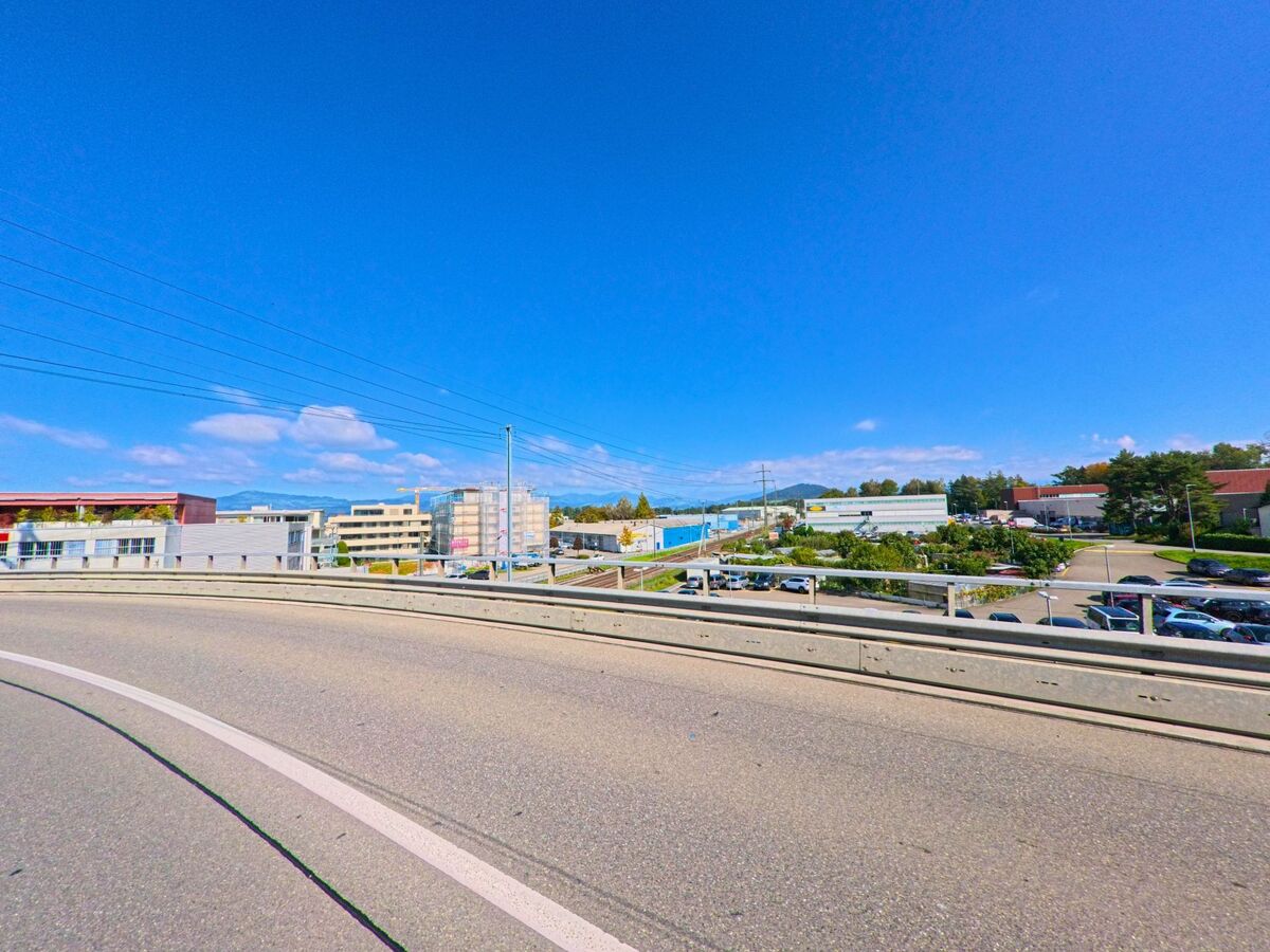 Eine breite Strasse führt durch ein Gebiet mit Industrie- und Wohnbauten in Lachen (8853, Kanton Schwyz).