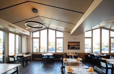 Der Landgasthof Weisses Kreuz in Leuggern (5316, Kanton Aargau) präsentiert einen hellen Gastraum mit grossen Fenstern, modernen Leuchten und festlich eingedeckten Tischen.