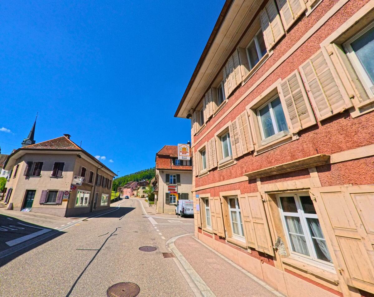 Im Zentrum von Langenbruck (4438, Kanton Baselland) treffen sich mehrere Strassen vor historischen Fassaden, im Hintergrund ist der Kirchturm deutlich sichtbar.