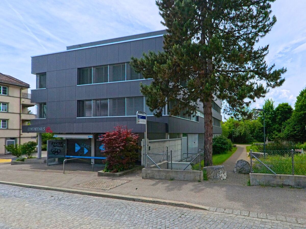 In Langendorf (4513, Kanton Solothurn) steht ein modernes Geschäftsgebäude mit gepflastertem Gehweg und Zugang zu einem begrünten Fussweg entlang eines Zauns.