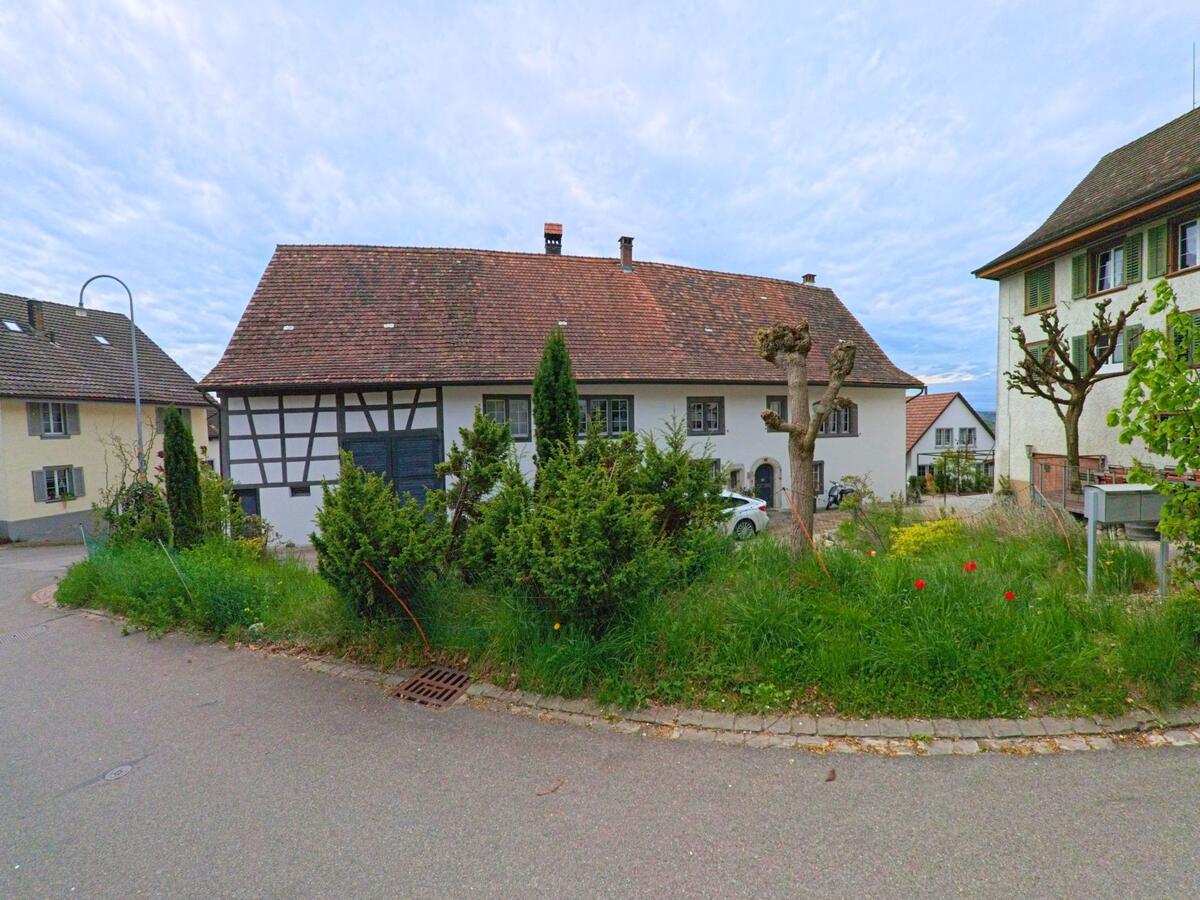In 8248 Laufen-Uhwiesen im Kanton Zürich steht ein traditionelles Fachwerkhaus mit gepflegtem Vorgarten inmitten eines historischen Dorfensembles.