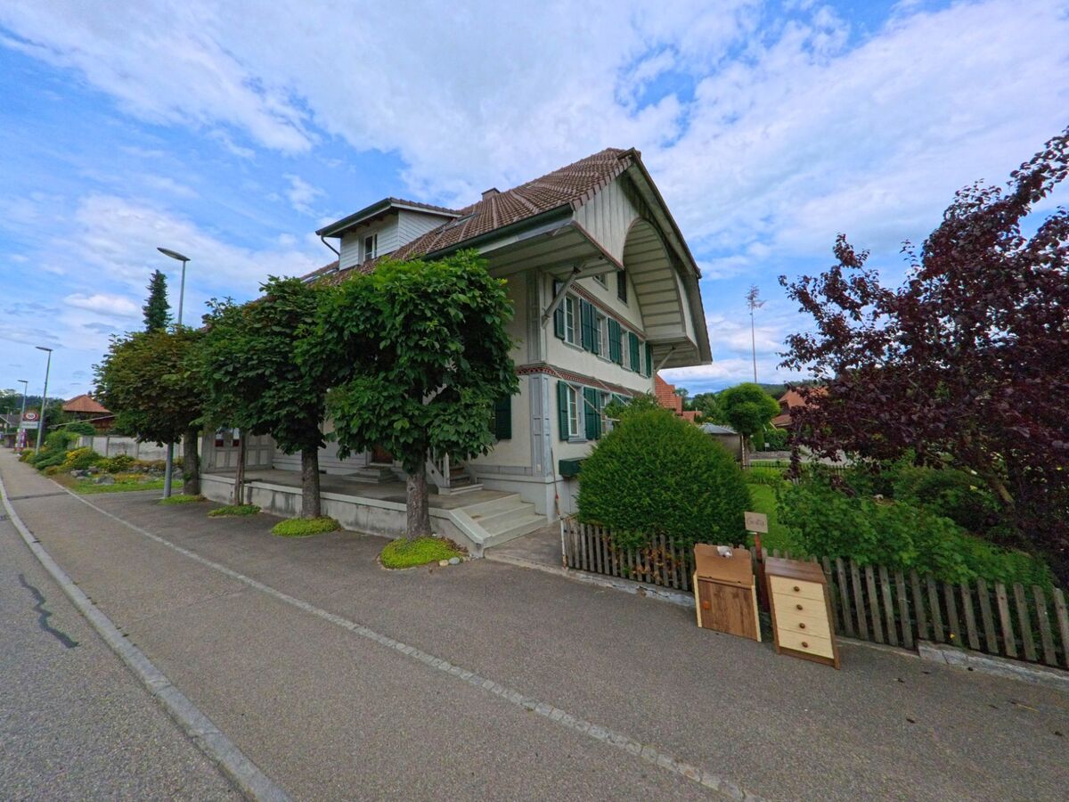 In Lauperswil (3436, Kanton Bern) steht ein traditionelles Haus mit gruenen Fensterlaeden an einer ruhigen Strasse, wo aussortierte Moebel zur Abgabe bereitstehen.