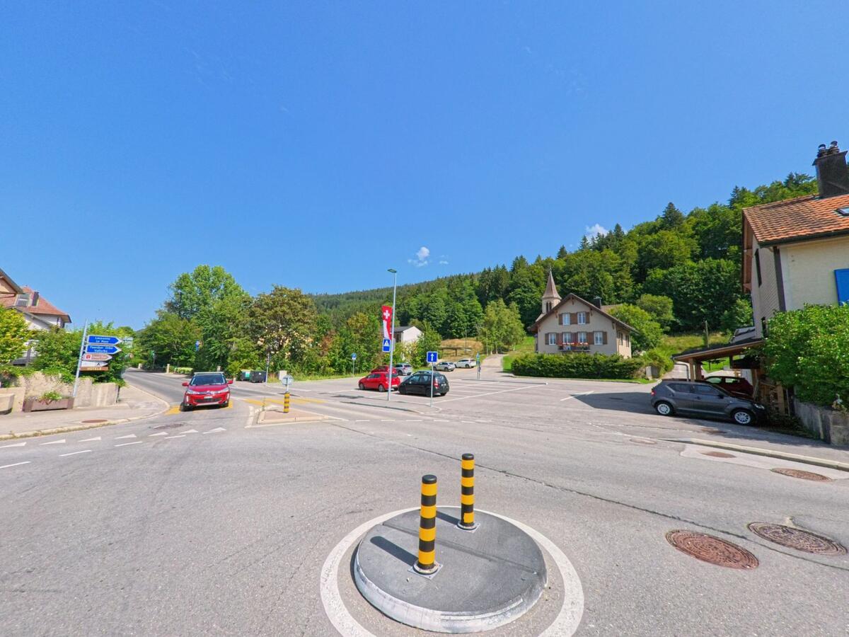 An einer Strassenkreuzung in Le Chenit (1348, Kanton Waadt) befindet sich ein Kammerjaeger-Einsatz in der Naehe eines Wohnhauses mit Kirchturm im Hintergrund.