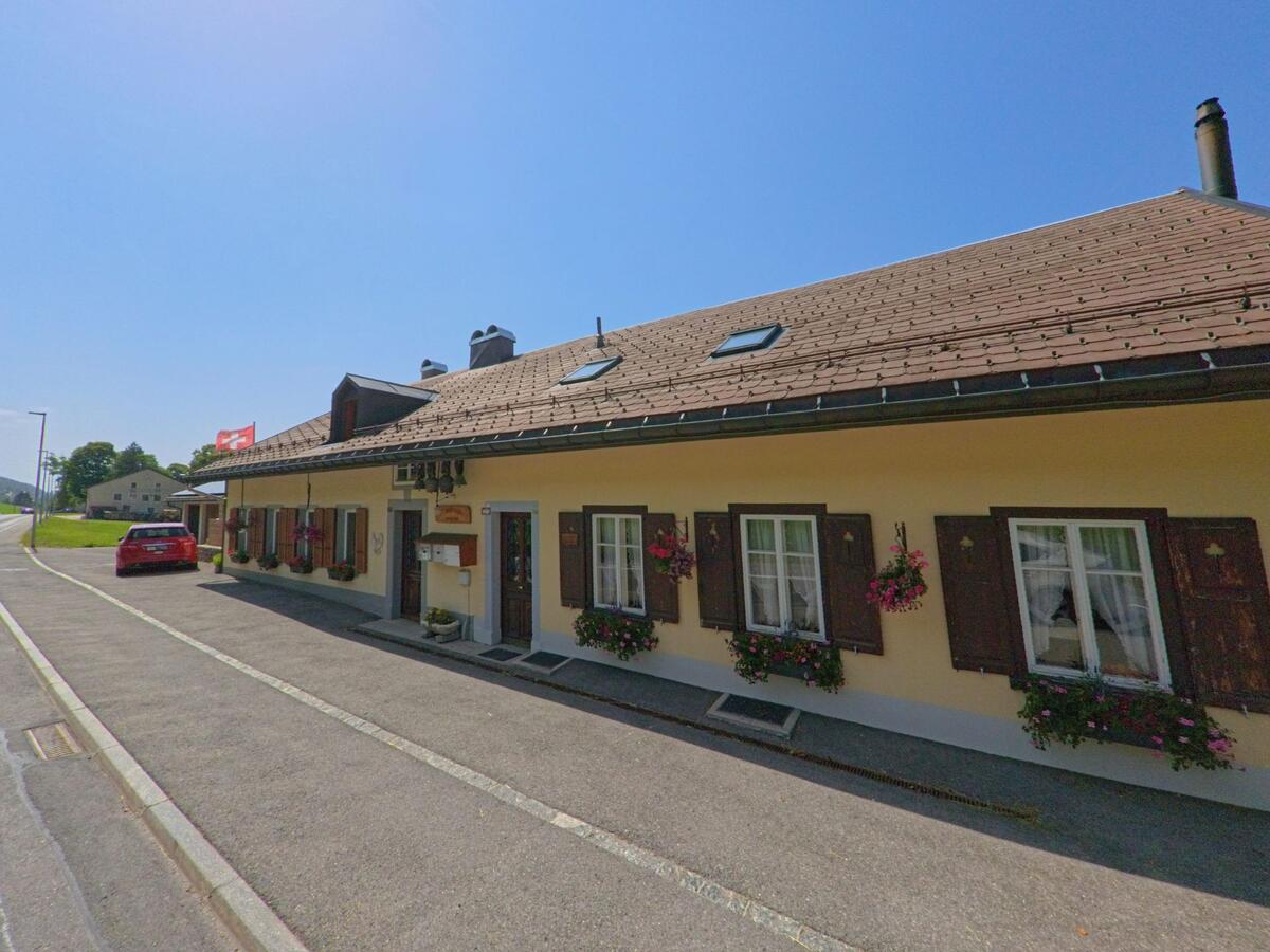 In Le Chenit (1348, Kanton Waadt) untersucht ein Kammerjaeger ein langgezogenes Wohnhaus mit Blumenkaesten und braunen Fensterlaeden.