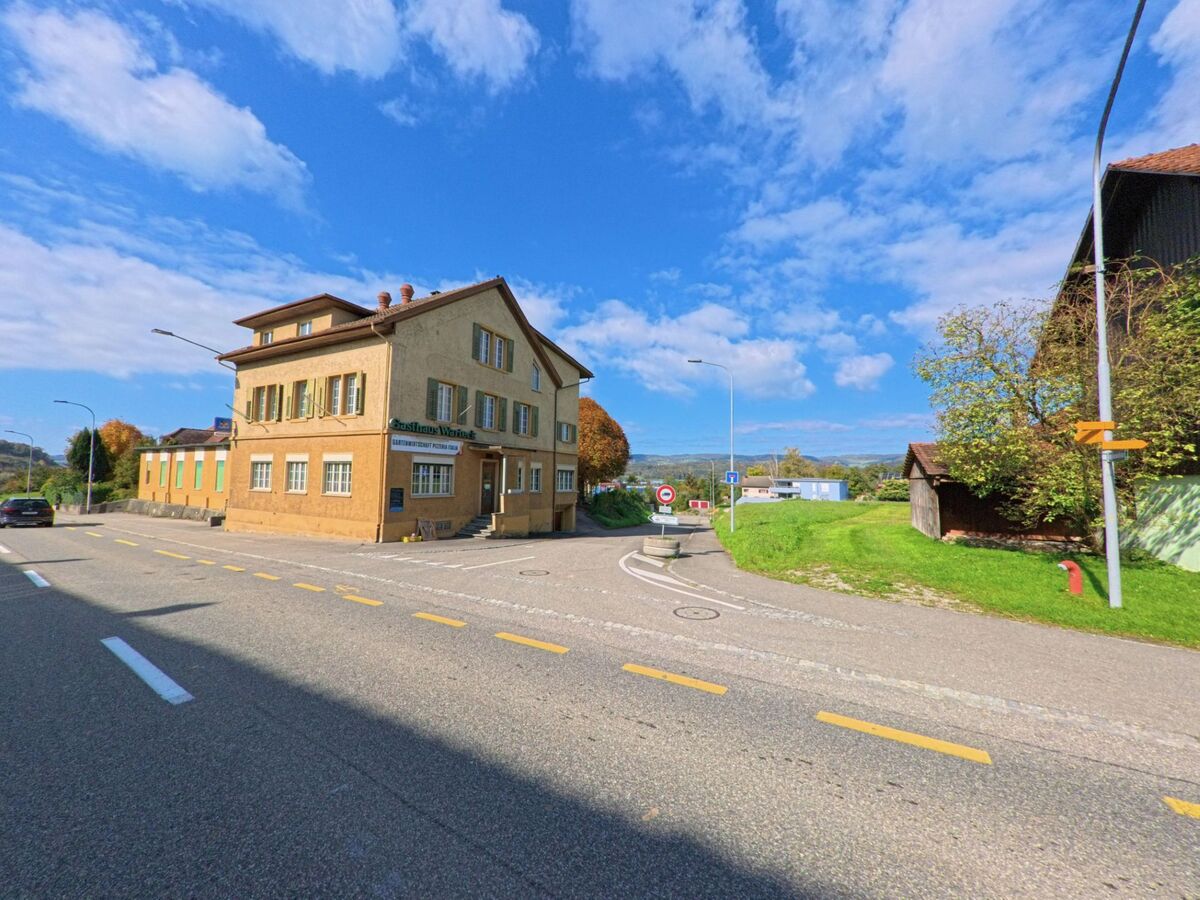 Das Gasthaus Wiesental in Leibstadt (5325, Kanton Aargau) steht an einer sonnigen Strassenecke, umgeben von Wiesen und Wohnhaeusern.