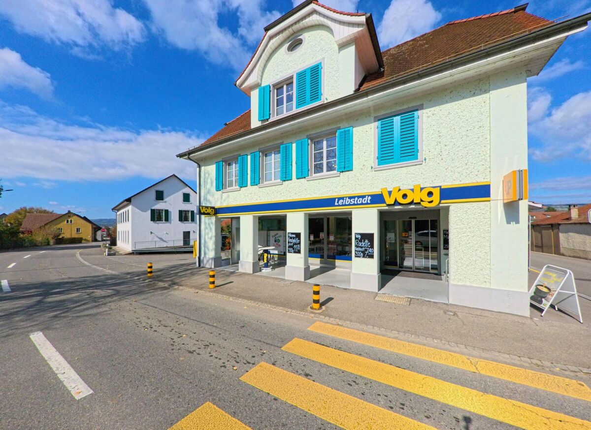 Das Volg-Geschaeft in Leibstadt (5325, Kanton Aargau) befindet sich in einem hellgruenen Gebaeude mit blauen Fensterlaeden an der Hauptstrasse.