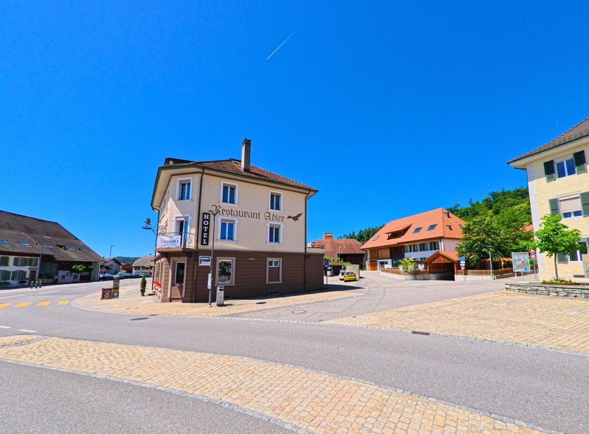 In Lengnau (2543, Kanton Bern) steht ein Restaurant mit Hotel an einer Straßenecke, umgeben von traditionellen Gebäuden und sonnigem Himmel.