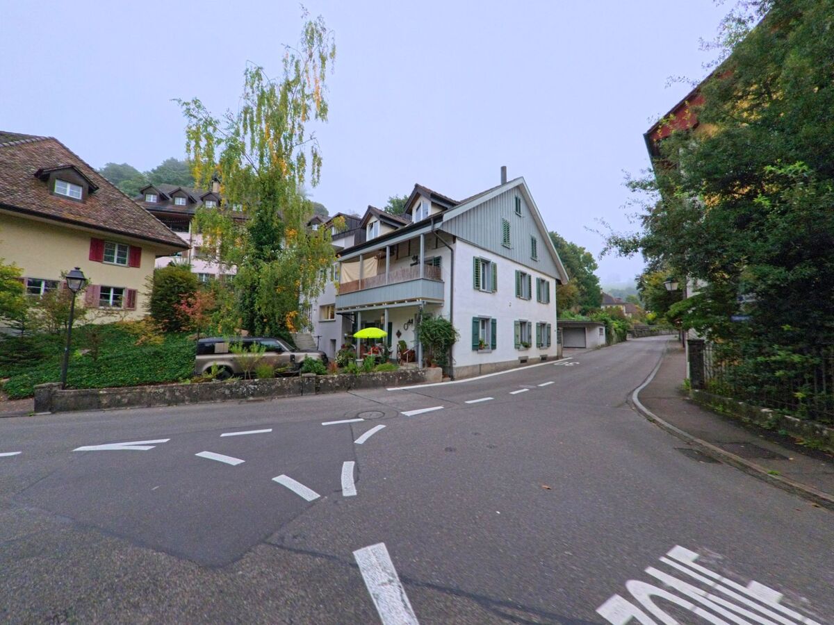Ein ruhiges Wohnquartier in Lenzburg (5600, Kanton Aargau) mit traditionellen Häusern und einer leicht ansteigenden Strasse, gesäumt von Bäumen.