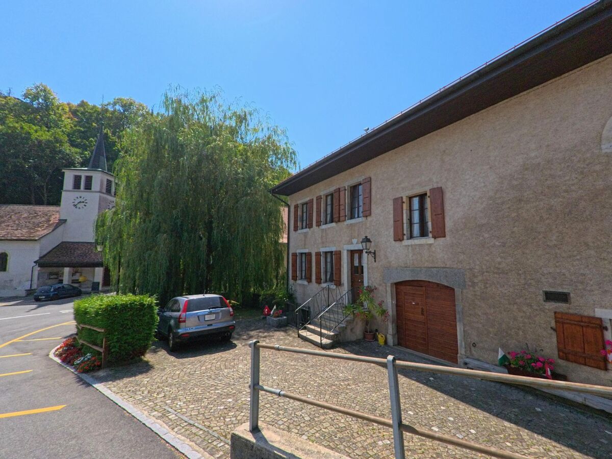 Im Zentrum von Les Clées (1356, Kanton Waadt) stehen traditionelle Wohnhaeuser neben der Dorfkirche mit ihrem markanten Turm und Uhrzifferblatt.