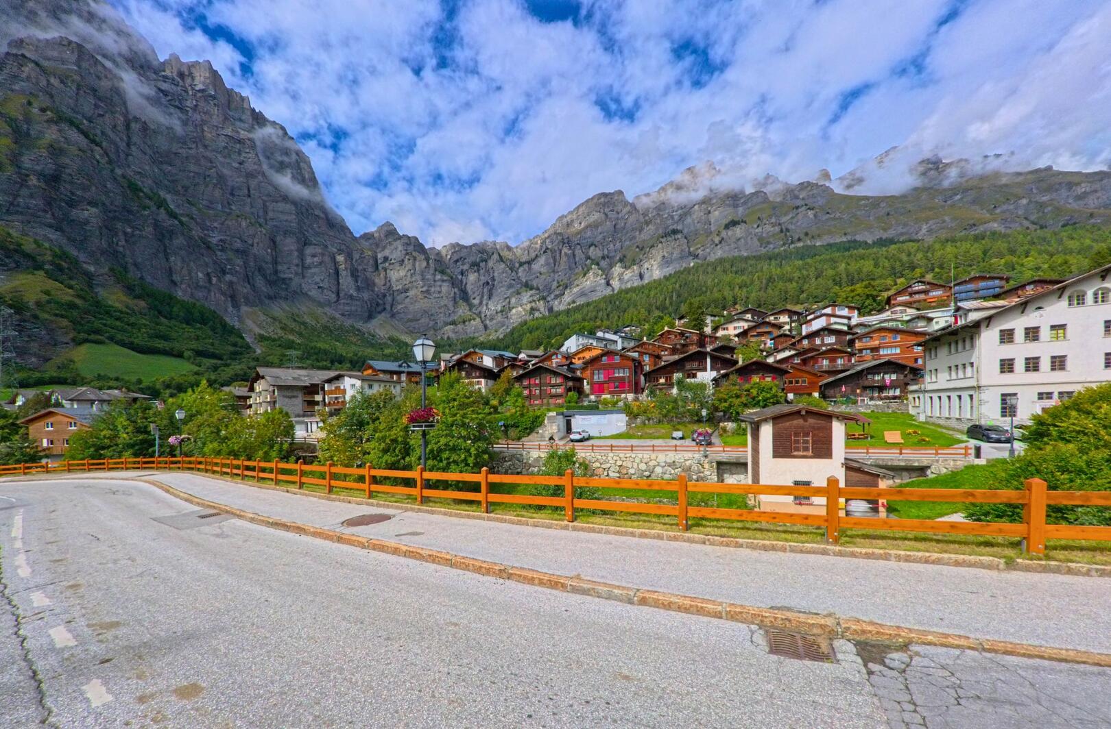 Vor den steilen Felswaenden erhebt sich das Dorf Leukerbad (3954, Kanton Wallis) mit seinen traditionellen Holzhäusern in terrassenfoermiger Anordnung.