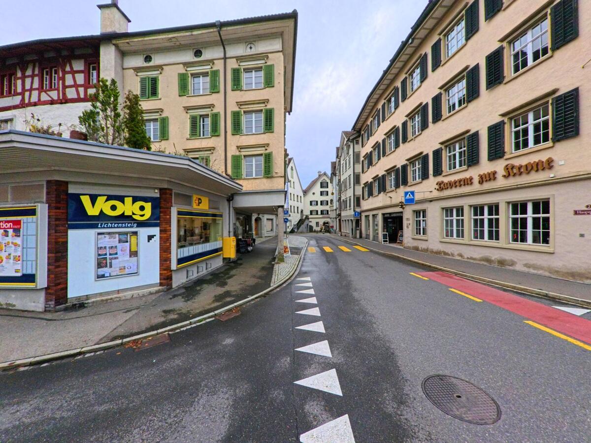 Entlang der schmalen Hauptgasse in Lichtensteig (9620, Kanton St. Gallen) stehen ein Volg-Laden und historische Fassaden mit markanten Fensterlaeden.