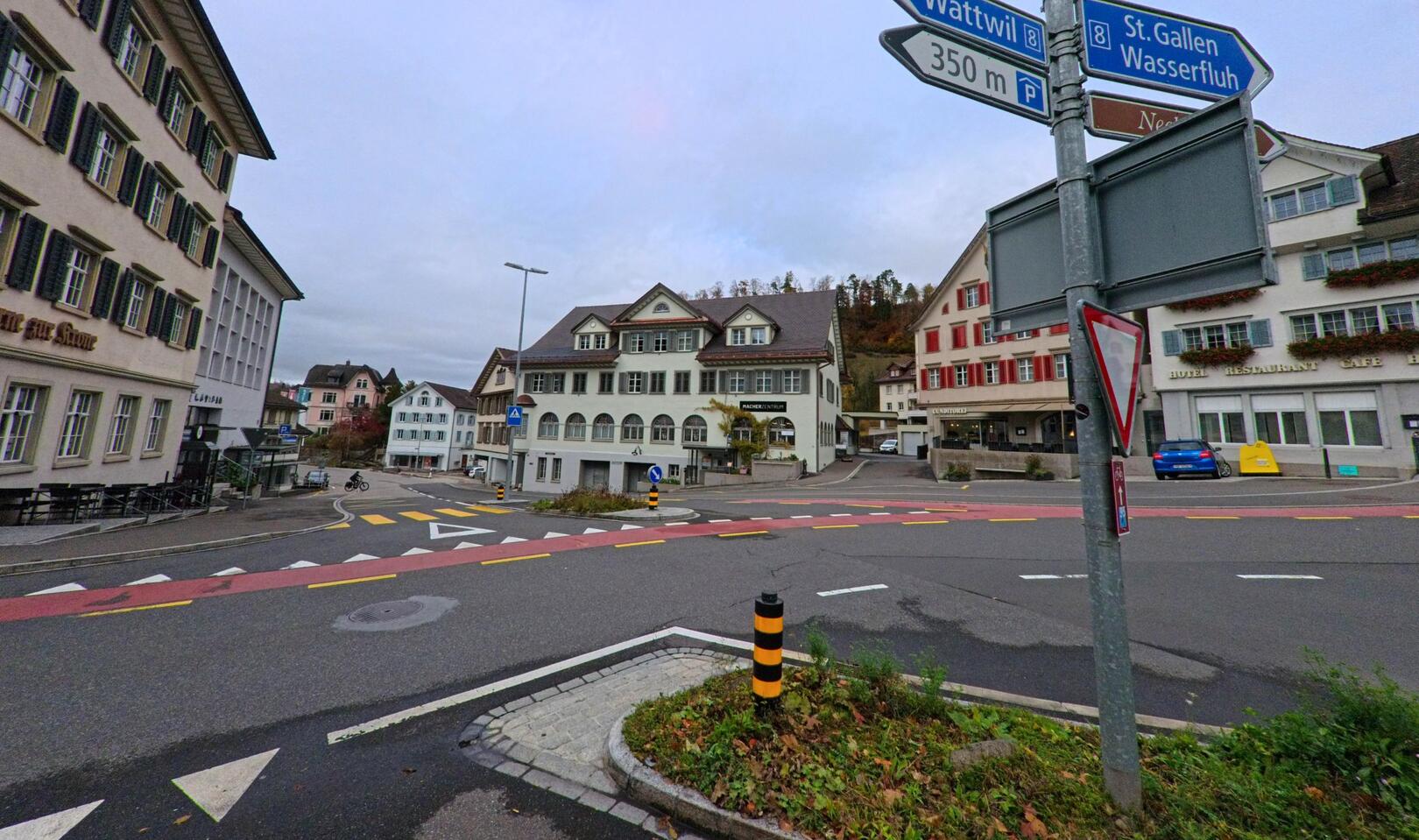 Vor den historischen Gebäuden im Ortszentrum von Lichtensteig (9620, Kanton St. Gallen) verläuft eine verzweigte Verkehrskreuzung mit markierten Fahrbahnen und Wegweisern.