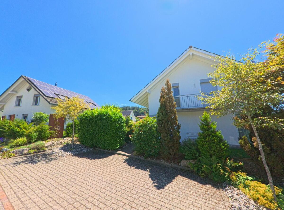 Zwei moderne Einfamilienhaeuser mit gepflegtem Vorgarten stehen in Lotzwil (4932, Kanton Bern), eines davon ist mit einer grossen Solaranlage auf dem Dach ausgestattet.