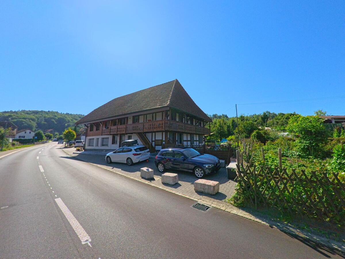 In Lüscherz (2576, Kanton Bern) steht ein traditionelles Bauernhaus mit Holzgalerie und angrenzendem Garten direkt an der Hauptstrasse.