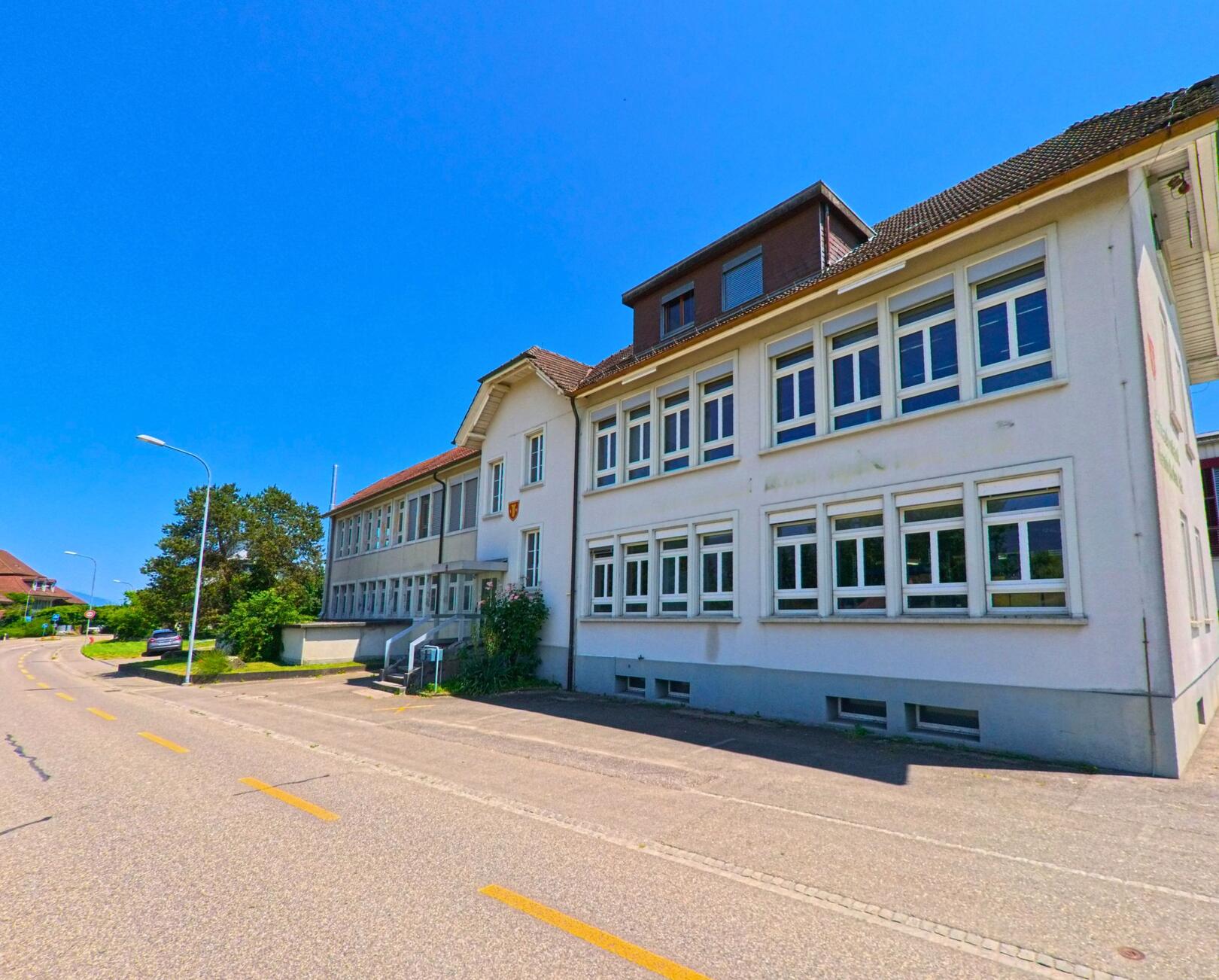 In Lüsslingen-Nennigkofen (4574, Kanton Solothurn) steht das helle Gebaeude der Schraubenfabrik Nennigkofen AG direkt an einer sanft geschwungenen Dorfstrasse.