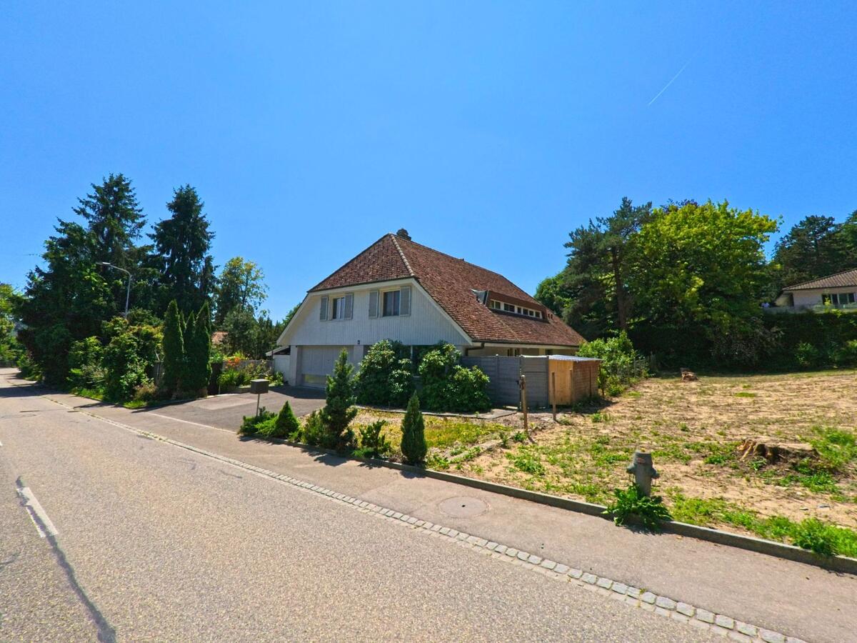 In einem Wohnquartier von Lüterkofen-Ichertswil (4571, Kanton Solothurn) steht ein Einfamilienhaus mit gepflegtem Vorplatz neben einem unbebauten Grundstück.