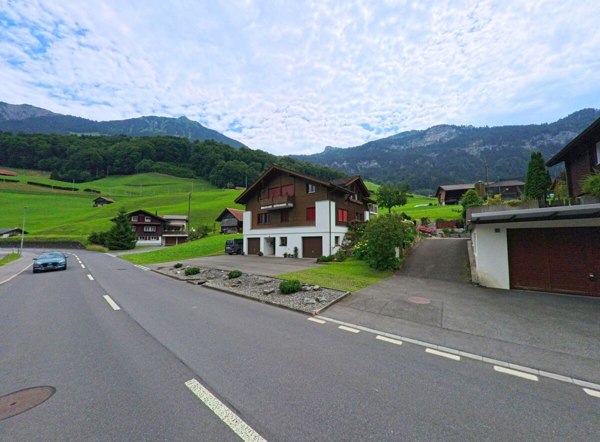 Am sonnigen Hang in Lungern (6078, Kanton Obwalden) reihen sich moderne Einfamilienhäuser mit gepflegten Gärten entlang einer ruhigen Strasse vor bewaldetem Bergpanorama.