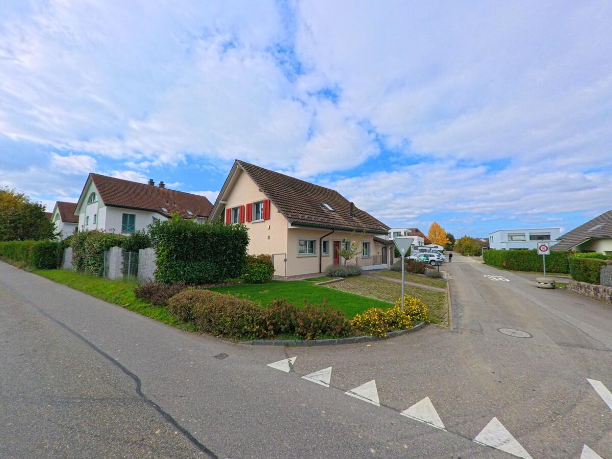 In einem ruhigen Wohnquartier von Lupfig (5242, Kanton Aargau) stehen gepflegte Einfamilienhäuser mit Gärten und Hecken entlang einer Nebenstrasse.