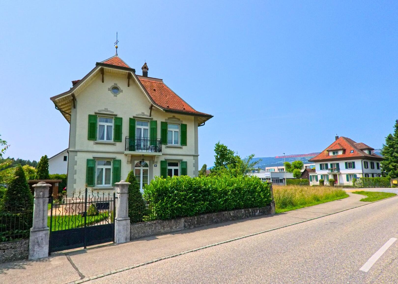 In Luterbach (4542, Kanton Solothurn) steht ein elegantes Haus mit grünen Fensterläden an einer ruhigen Strasse, umgeben von gepflegten Gärten und einer auffälligen Einfahrt.