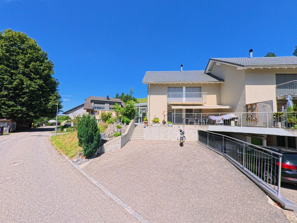 In einem ruhigen Wohnquartier von Luthern (6156, Kanton Luzern) stehen gepflegte Einfamilienhäuser mit Terrassen und Garagenzufahrten entlang einer leicht geschwungenen Strasse.