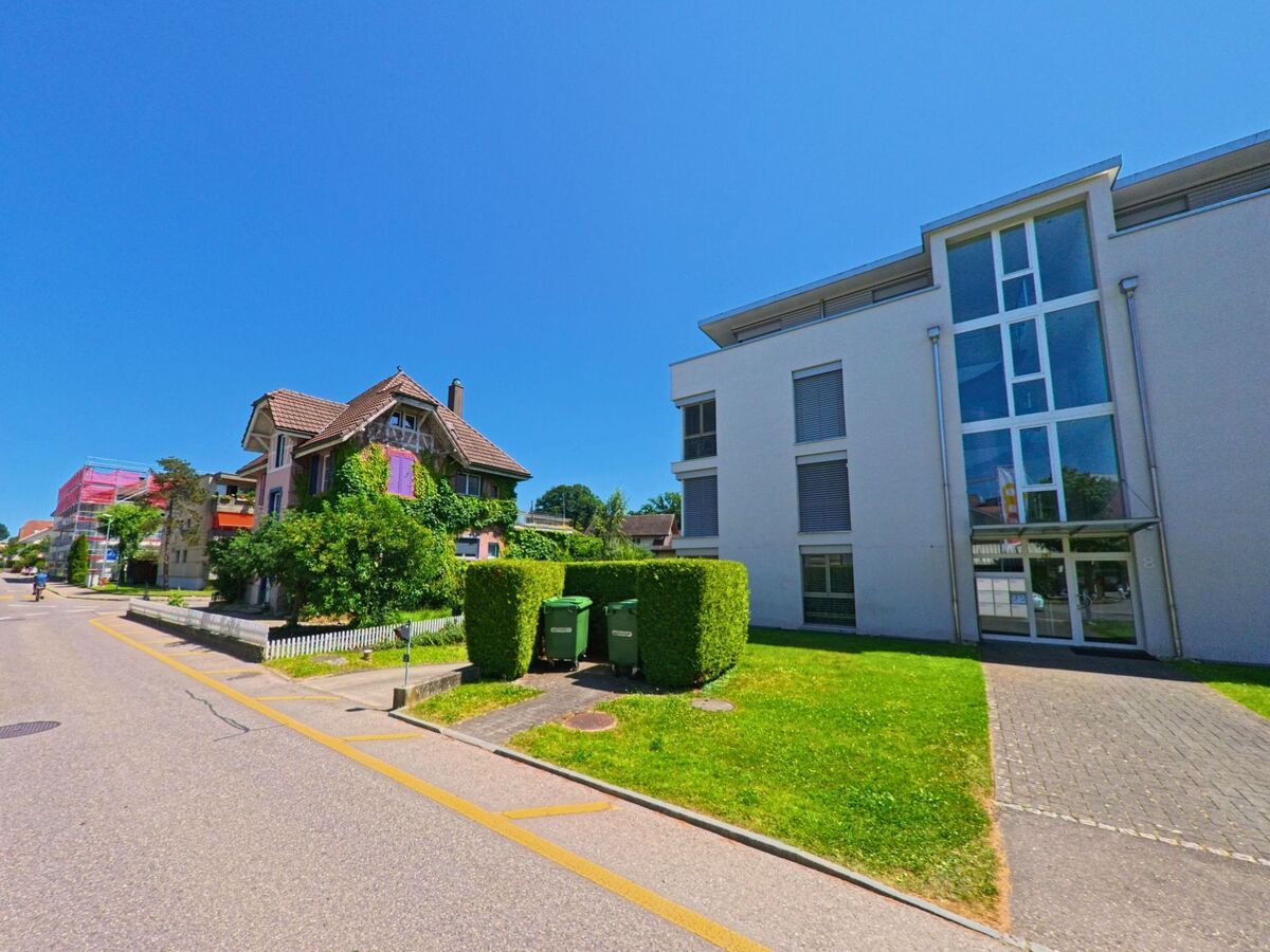 In Lyss (3250, Kanton Bern) treffen ein modernes Wohnhaus mit grossen Fensterfronten und eine mit Efeu bewachsene Altbauvilla aufeinander.