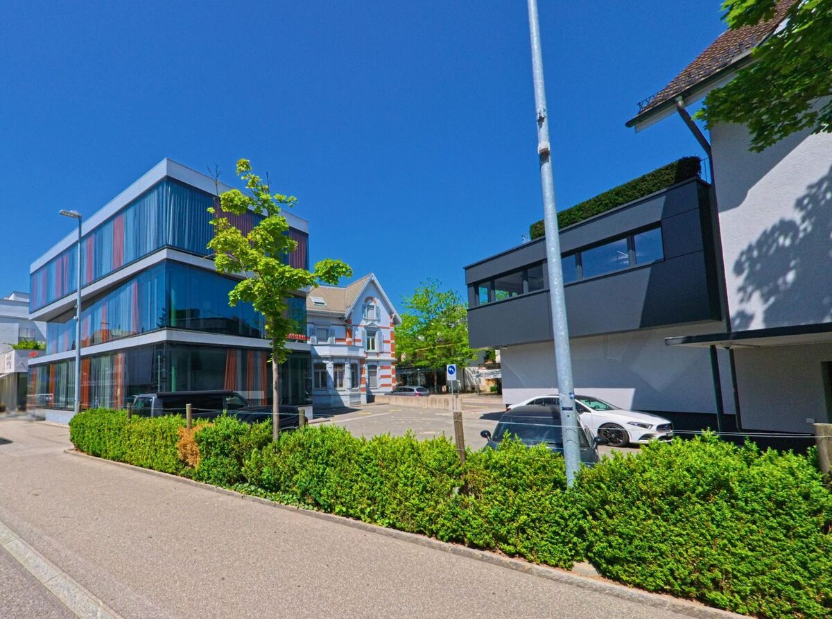 In Lyss (3250, Kanton Bern) stehen moderne Glasbauten mit farbigen Vorhängen neben einem renovierten Altbau mit historischer Fassade.