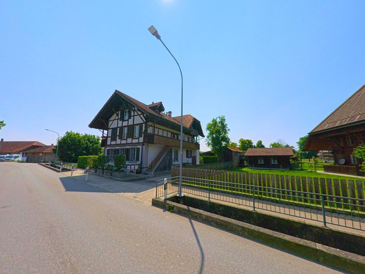 In Lyssach (PLZ 3421, Kanton Bern) steht ein traditionelles Wohnhaus mit sichtbarem Fachwerk an einer ruhigen Seitenstrasse neben gepflegten Gärten und Nebengebäuden.