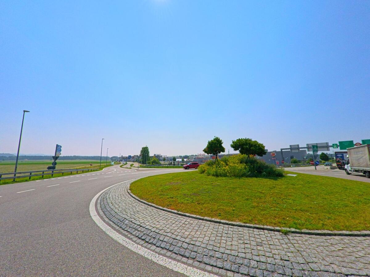  In Lyssach (PLZ 3421, Kanton Bern) liegt ein Kreisverkehr mit begrüntem Mittelstreifen am Übergang zwischen landwirtschaftlicher Fläche und Einkaufs- sowie Industriegebiet.