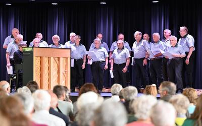 Vor Publikum singt der Männerchor in Aristau (5628, Kanton Aargau) auf einer Bühne und wird dabei am Klavier begleitet.