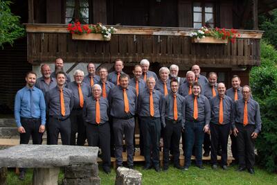 Vor einem Holzhaus in Madiswil (4935, Kanton Bern) steht eine Gruppe von Maennern in einheitlicher Kleidung fuer ein gemeinsames Gruppenfoto.