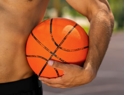 In Rüti bei Büren (3295, Kanton Bern) hält eine Person einen Basketball unter dem Arm, während die Szene im Freien stattfindet.