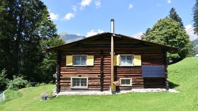 Das Maiensaess Hinter Tersana in Seewis im Praettigau (7215, Kanton Graubuenden) zeigt ein traditionelles Holzhaus mit gelben Fensterlaeden inmitten gruener Wiesen.