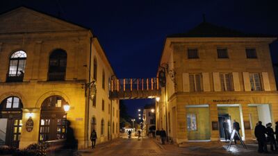 In Yverdon-les-Bains (1400, Kanton Waadt) liegt das Maison d’Ailleurs abends stimmungsvoll beleuchtet an einer schmalen Gasse zwischen historischen Gebaeuden.