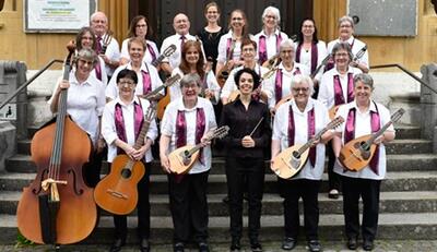 In Langenthal (4900, Kanton Bern) spielt ein Orchester mit Dirigentin auf einer Bühne und fuehrt ein Konzert mit verschiedenen Instrumenten auf.