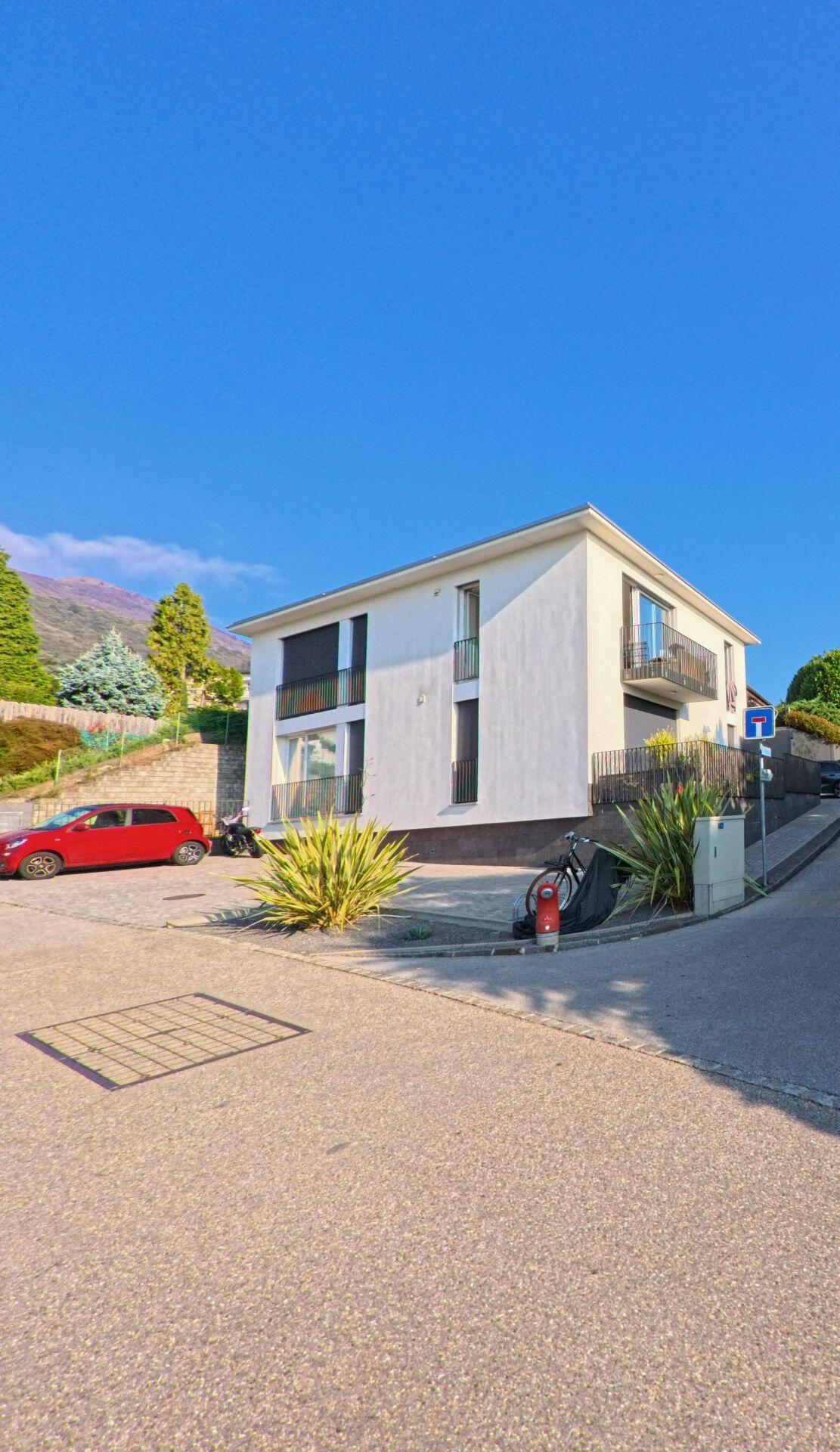 Ein modernes Wohnhaus mit Balkonen steht an einer ruhigen Strasse in Manno (6928, Kanton Tessin), umgeben von gepflegten Grünflächen und sanfter Hanglage.