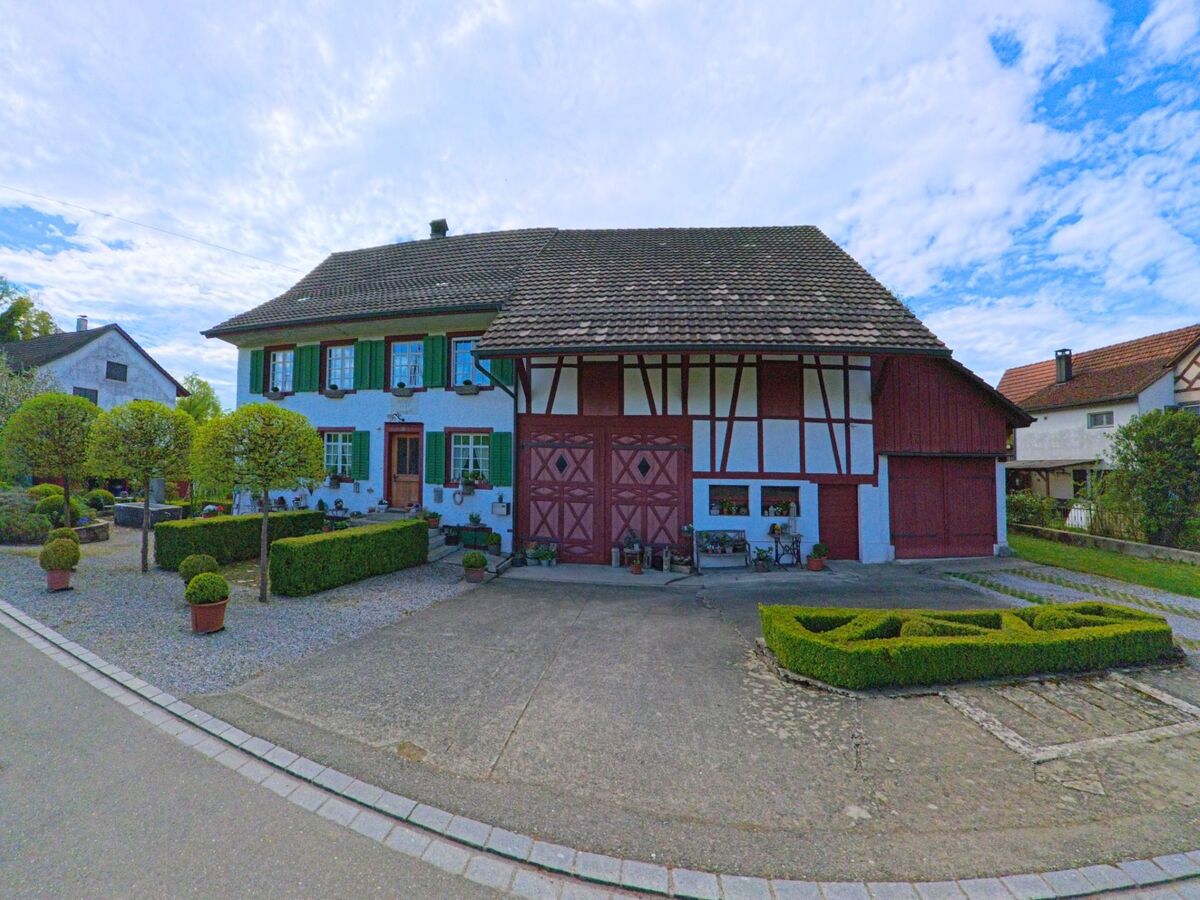 In der Gemeinde Marthalen im PLZ-Gebiet 8460 im Kanton Zürich steht ein liebevoll gepflegtes Fachwerkhaus mit grünem Fensterladen und symmetrisch angelegtem Ziergarten.