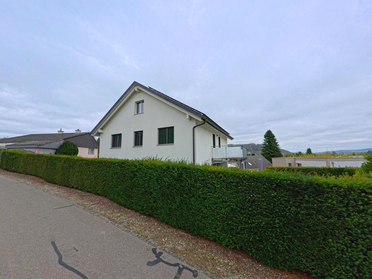 Hinter einer dicht geschnittenen Hecke steht in Matzingen (9548, Kanton Thurgau) ein helles Einfamilienhaus mit Balkon am Rand einer ruhigen Quartierstrasse.