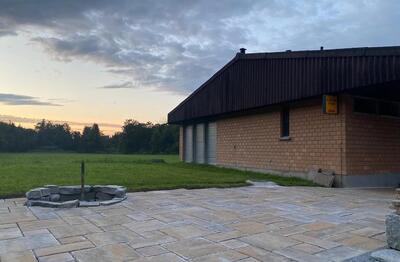 Auf einer gepflasterten Flaeche mit Schiessanlage zeigt sich in Matzingen (9548, Kanton Thurgau) ein Vereinsareal mit Gebaeude, Wiese und Feuerstelle bei Abendstimmung.