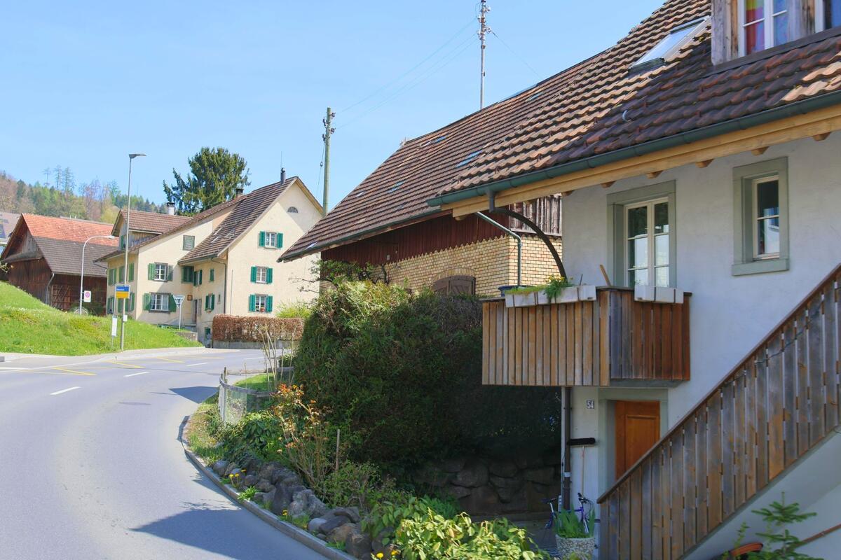 In Mettmenstetten, PLZ 8932 im Kanton Zürich verläuft eine kurvige Strasse an traditionellen Wohnhäusern und Scheunen mit Ziegeldächern und grünen Fensterläden vorbei.