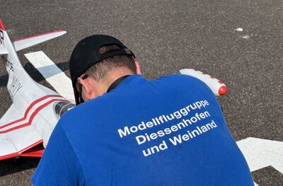 Eine Person bereitet ein Modellflugzeug auf einer Startflaeche in Diessenhofen (8253, Kanton Thurgau) vor und zeigt Modellflugaktivitaet.