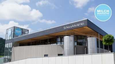 Die Milchmanufaktur Einsiedeln AG in Einsiedeln (8840, Kanton Schwyz) präsentiert ein modernes Gebäude mit grosser Glasfront und Edelstahl-Tanks für die Schaukäserei.