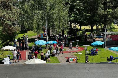 Auf einer Minigolfanlage verbringen Menschen in Bern (3000, Kanton Bern) gemeinsam Zeit zwischen Bahnen, Bäumen und Sitzplätzen im Park.
