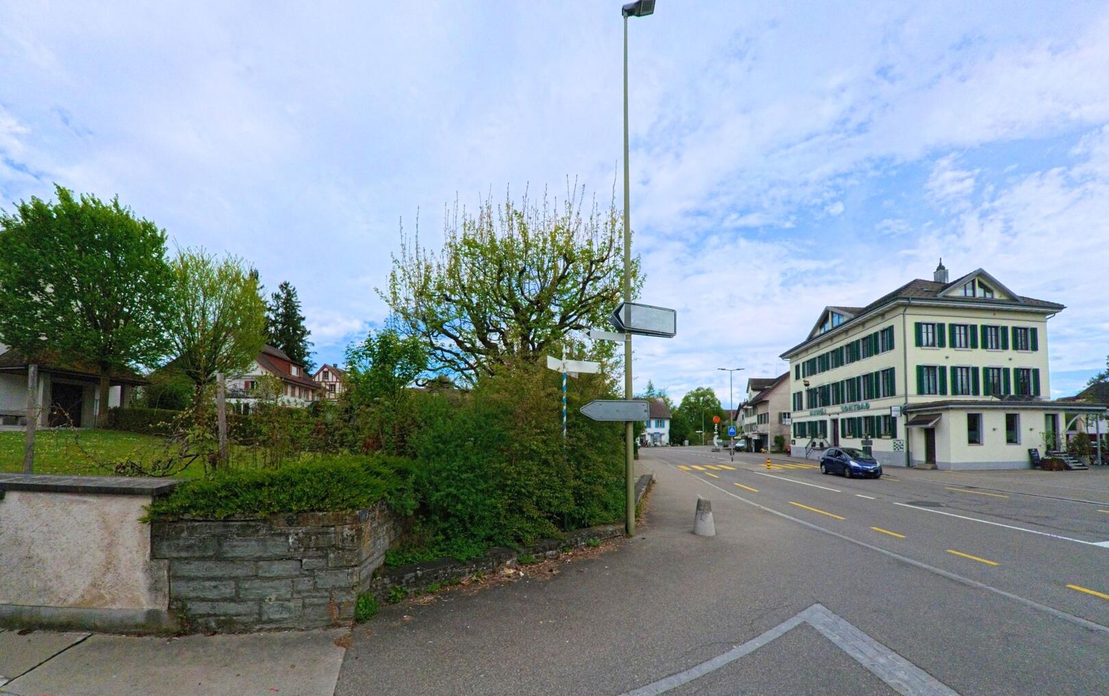 An der Hauptstrasse in Mönchaltorf (8617, Kanton Zürich) befindet sich ein Gebäude mit traditionellen grünen Fensterrahmen und ein Baum, der sich im Frühling zeigt.